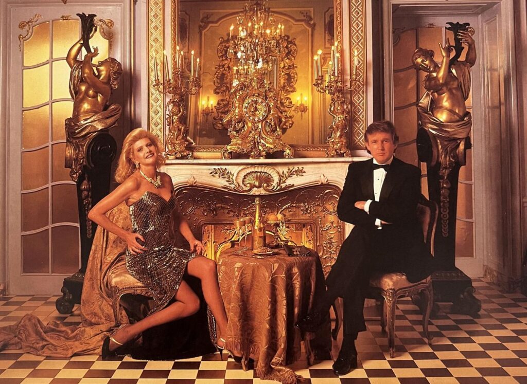 Donald e Ivana aparecem em um ambiente ricamente decorado do Plaza, com lareira, esculturas douradas e lustres. A fotografia traduz perfeitamente a estética de luxo dos anos 1980 | Foto: reprodução